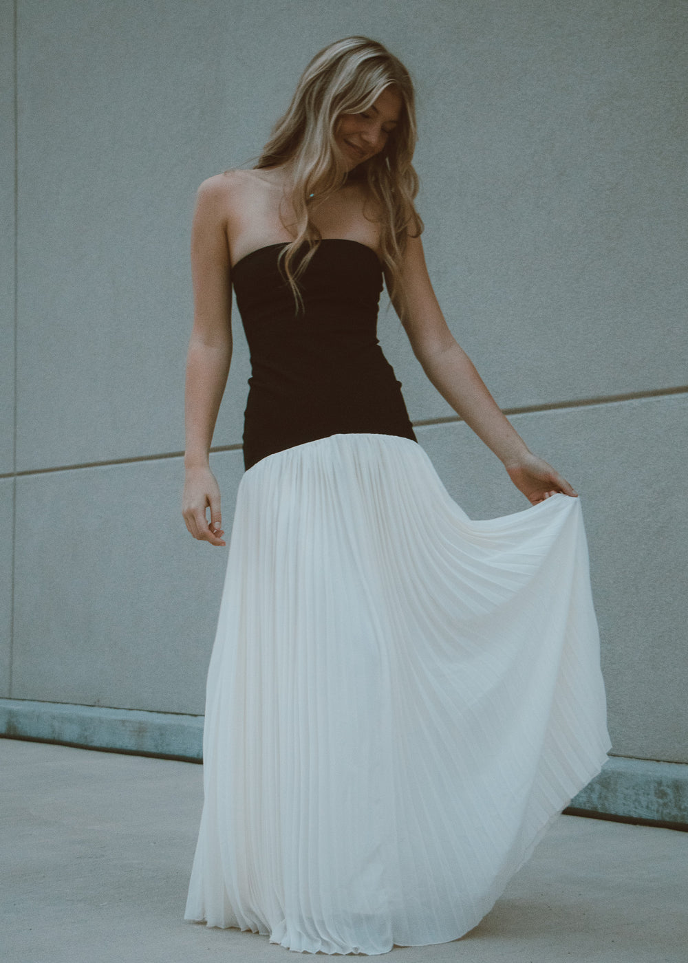 Woman wearing a black and white pleated dress against a neutral background