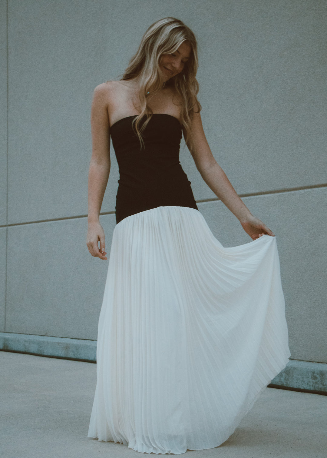 Woman wearing a black and white pleated dress against a neutral background