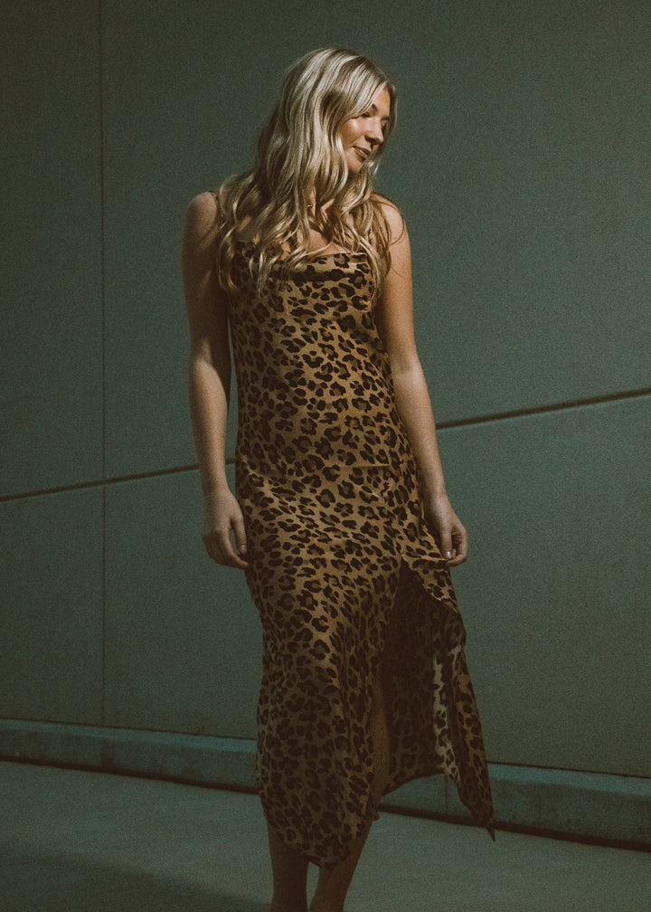 Woman wearing a leopard print dress against a plain background