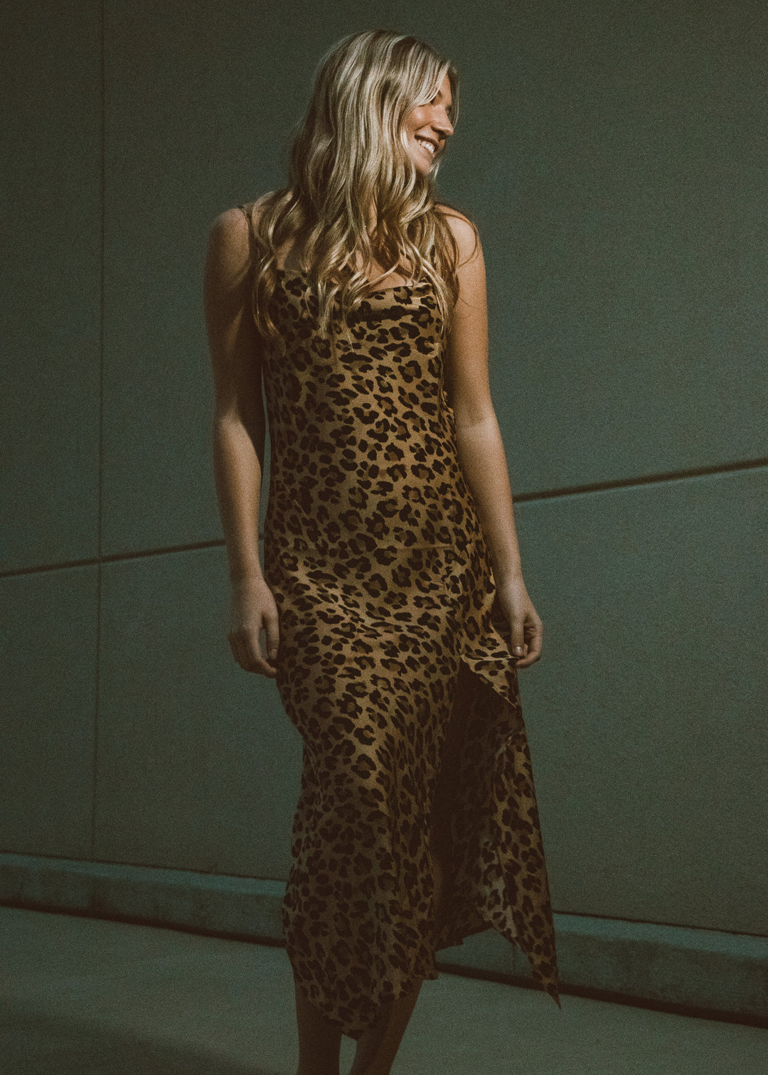 Woman wearing a leopard print dress against a green wall.