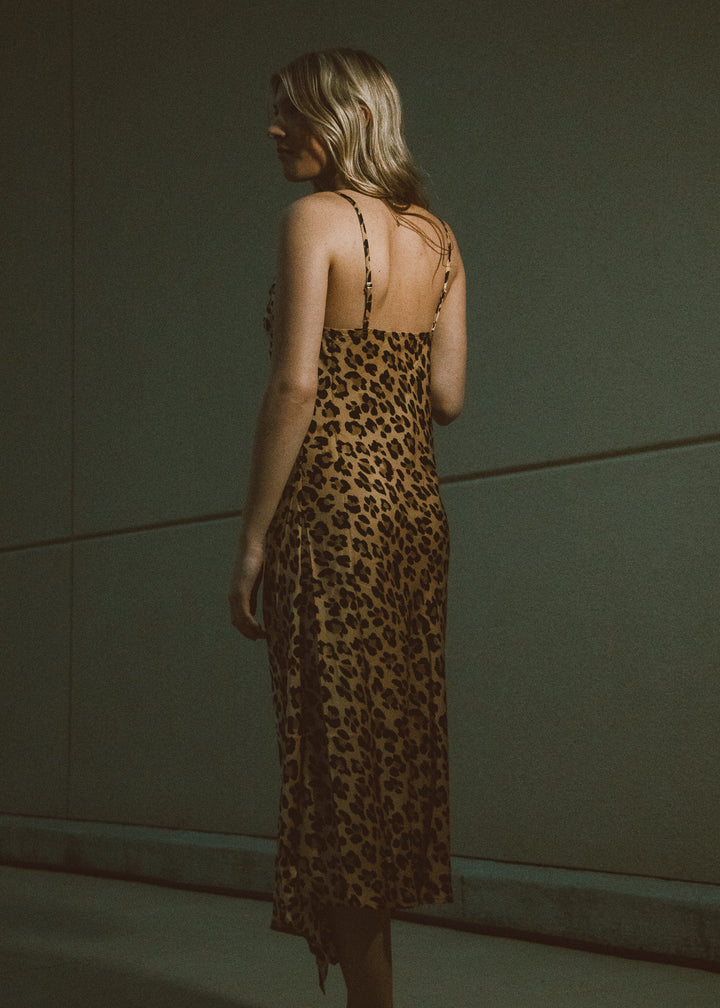 Woman wearing a leopard print dress against a plain background