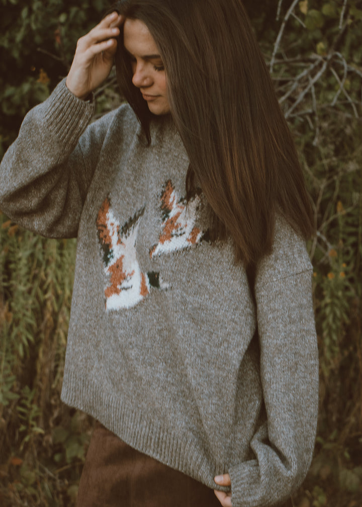 Woman wearing a sweater with duck designs in an outdoor setting
