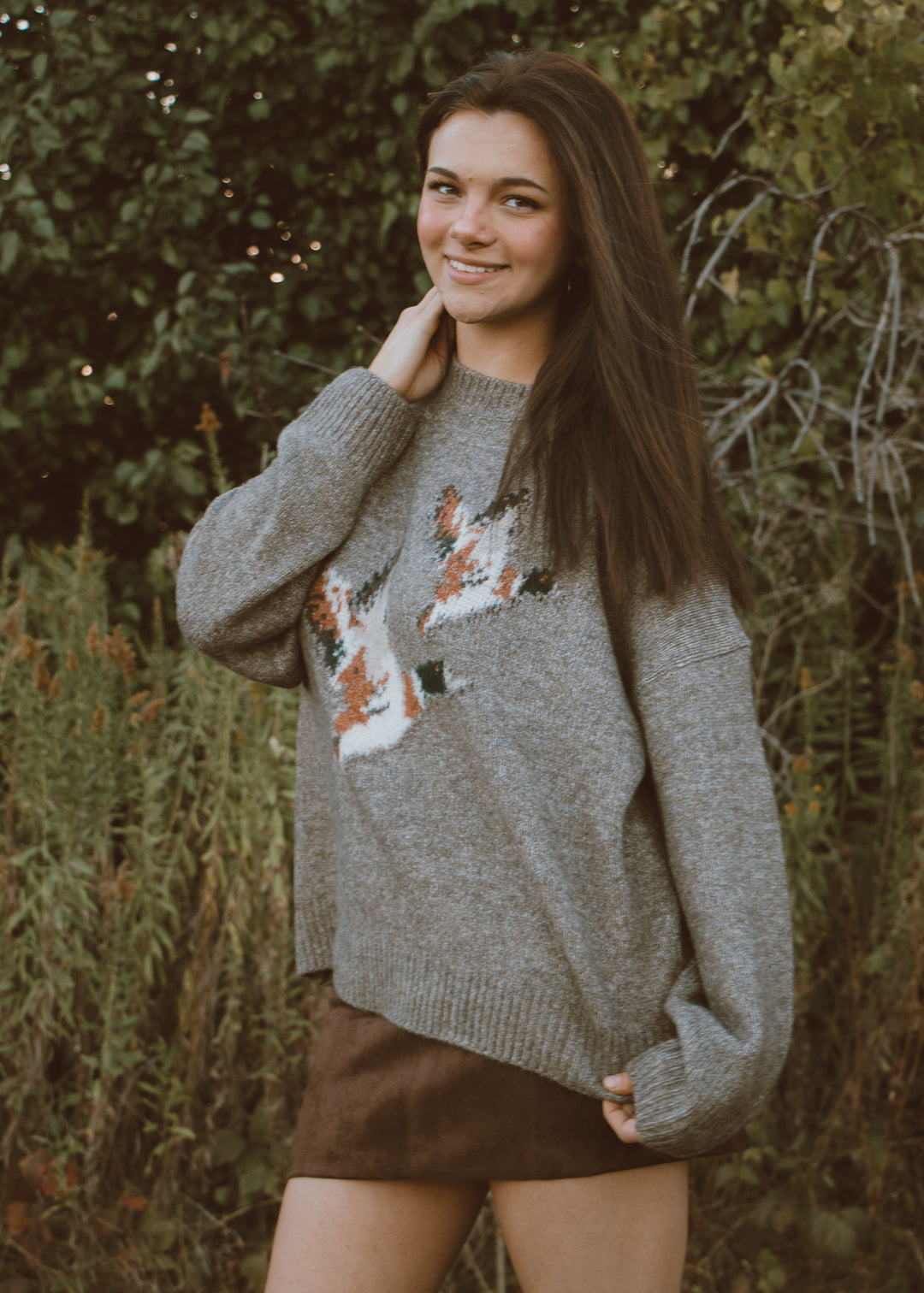Woman wearing a gray sweater with duck patterns outdoors