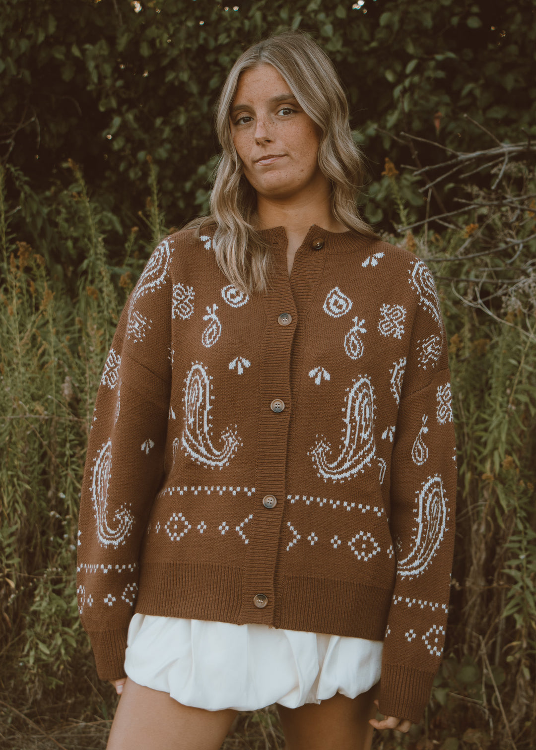 Woman wearing a brown paisley cardigan in a natural setting
