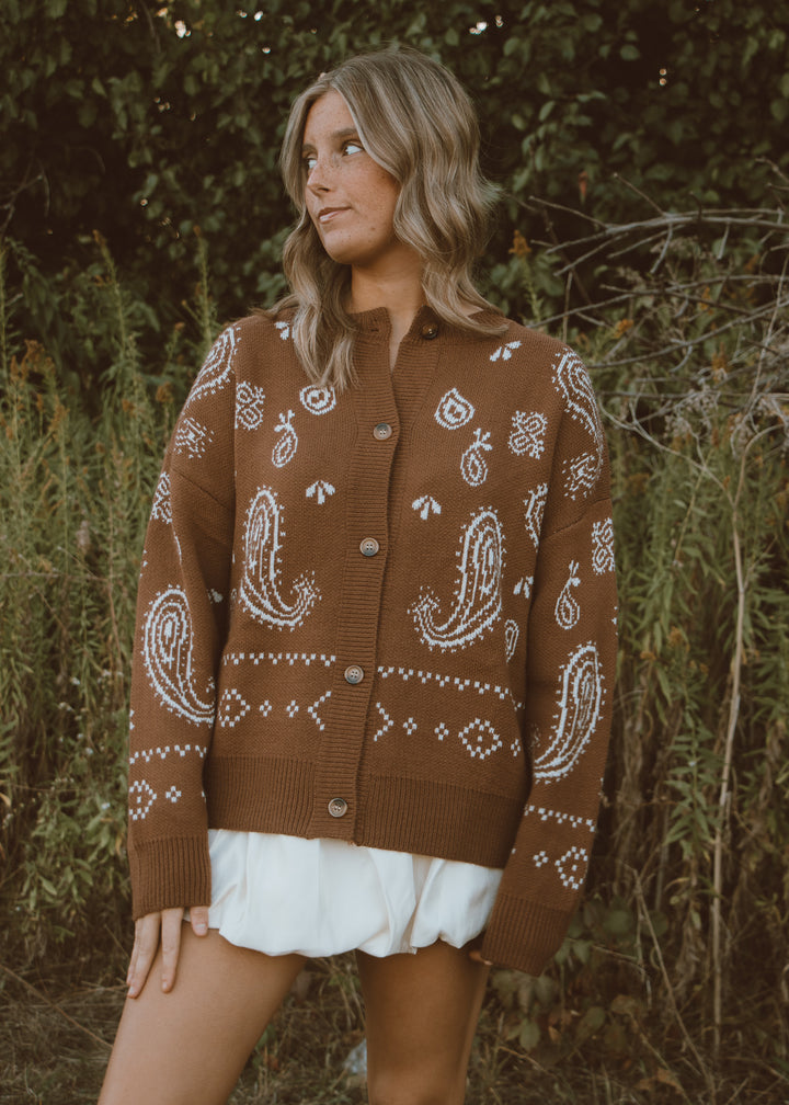 Woman wearing a brown paisley cardigan in a natural setting