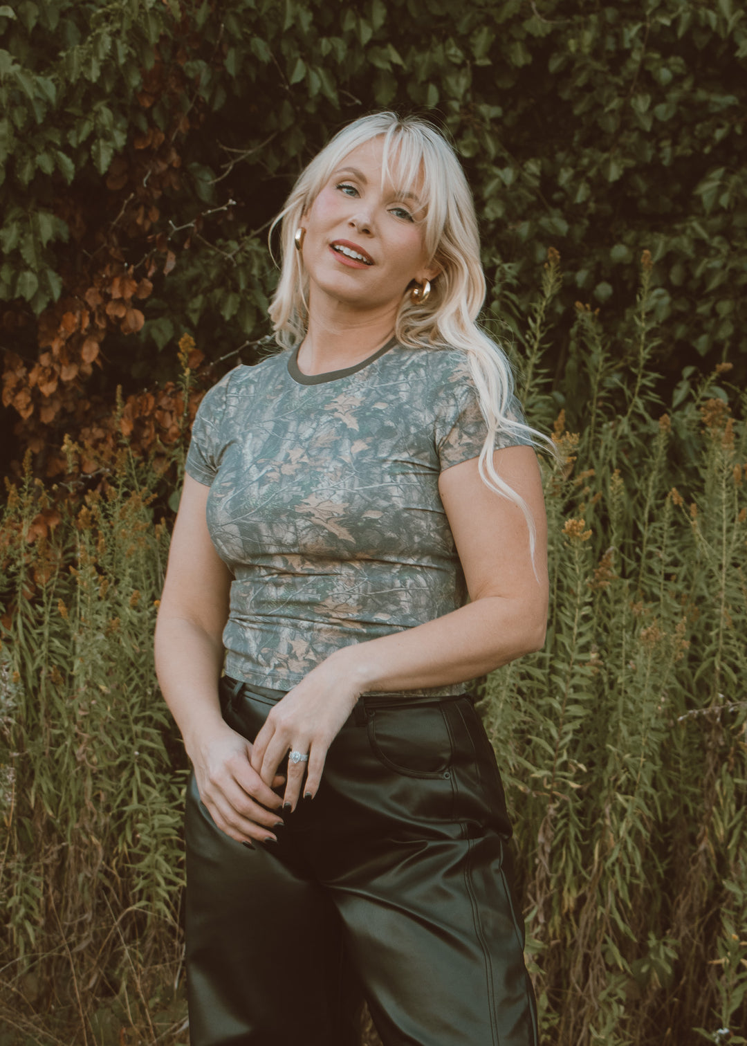 Woman in camo tee and leather pants.
