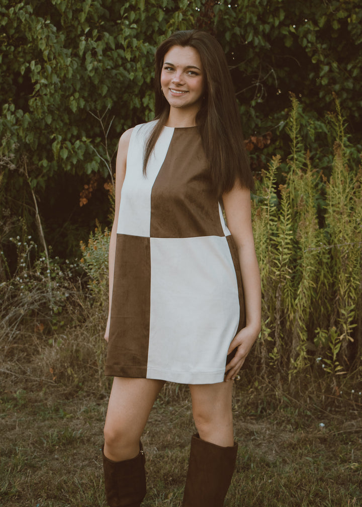 Woman wearing a brown and white dress standing in a natural setting