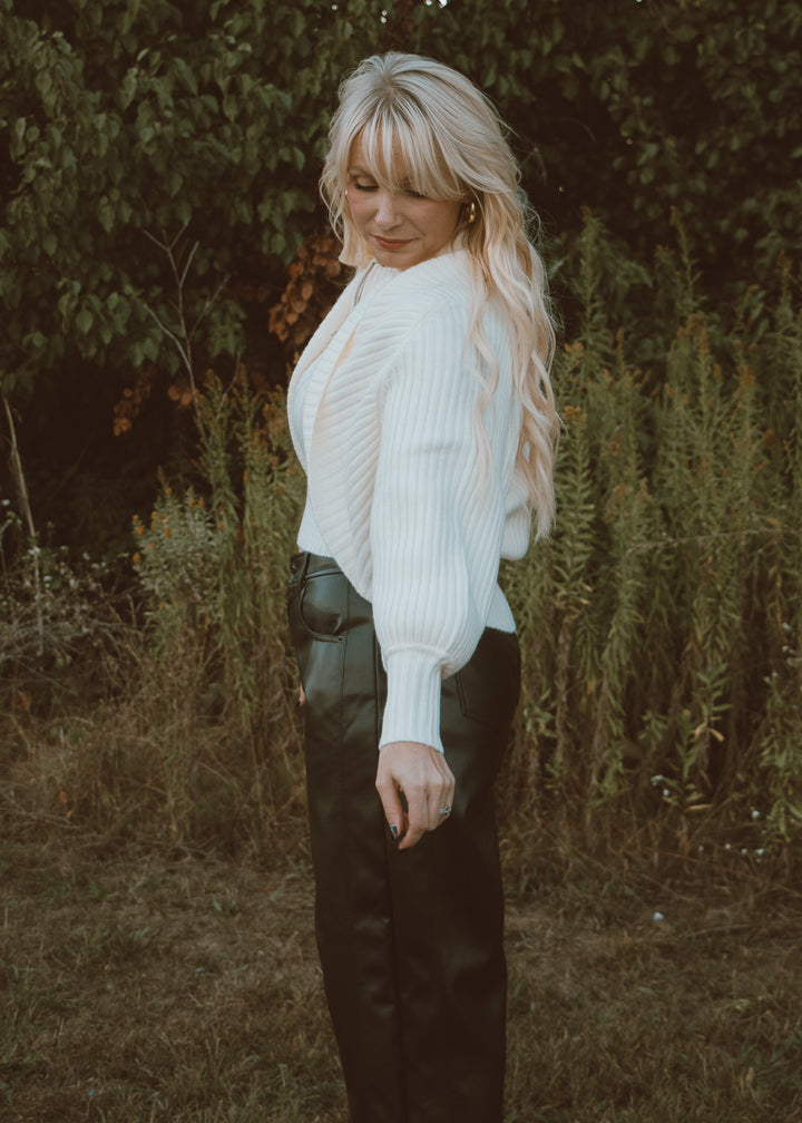white shrug sweater and leather pants.