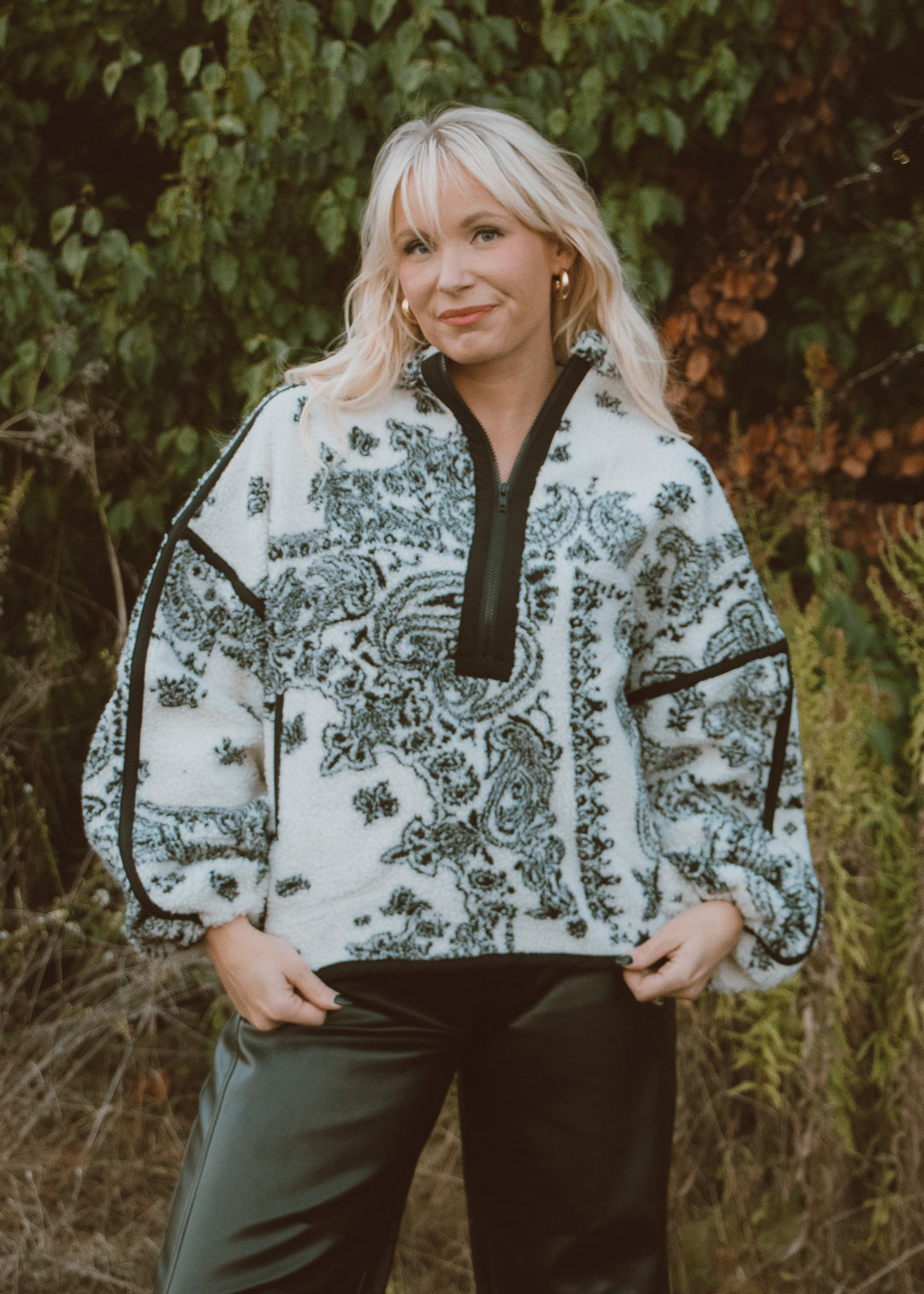 Woman wearing a patterned jacket standing in a natural setting
