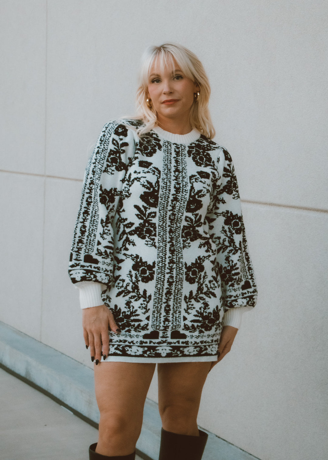Woman wearing a patterned dress standing against a plain background