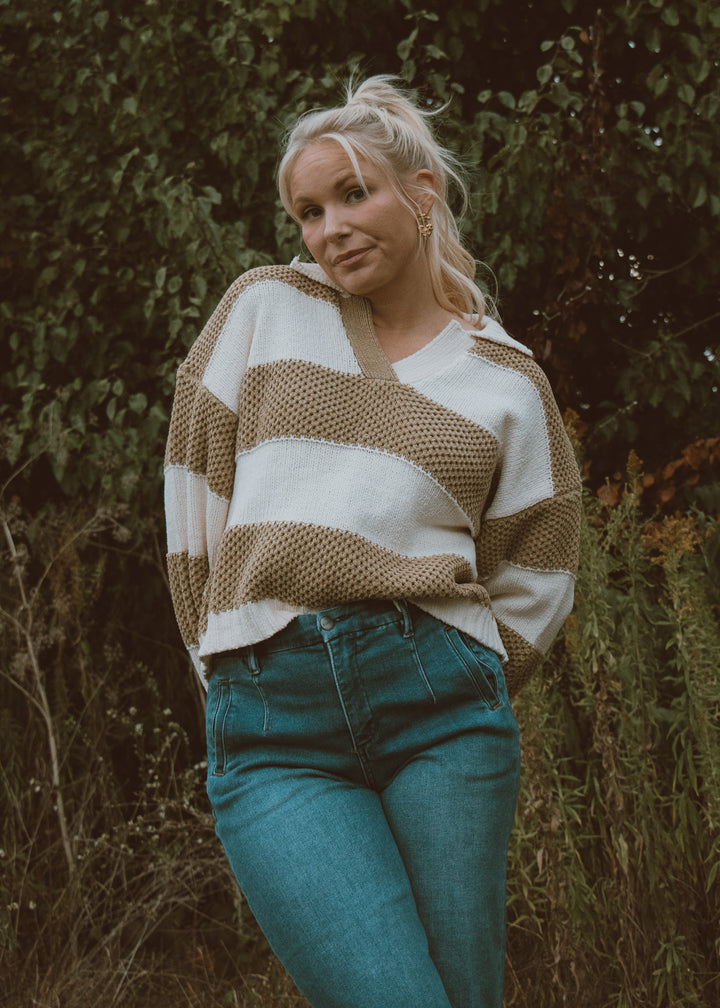 Woman wearing a striped sweater and jeans standing in a natural setting
