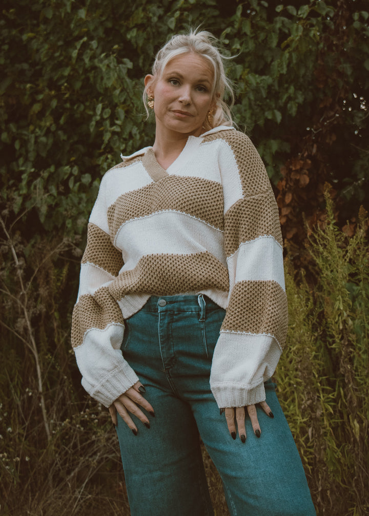 Woman wearing a patterned sweater and jeans standing in a natural setting