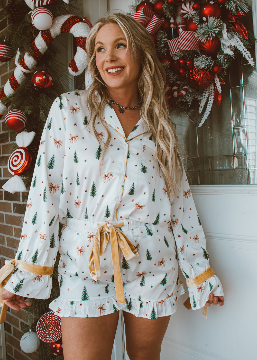 Woman wearing a festive pajama set with holiday decorations in the background