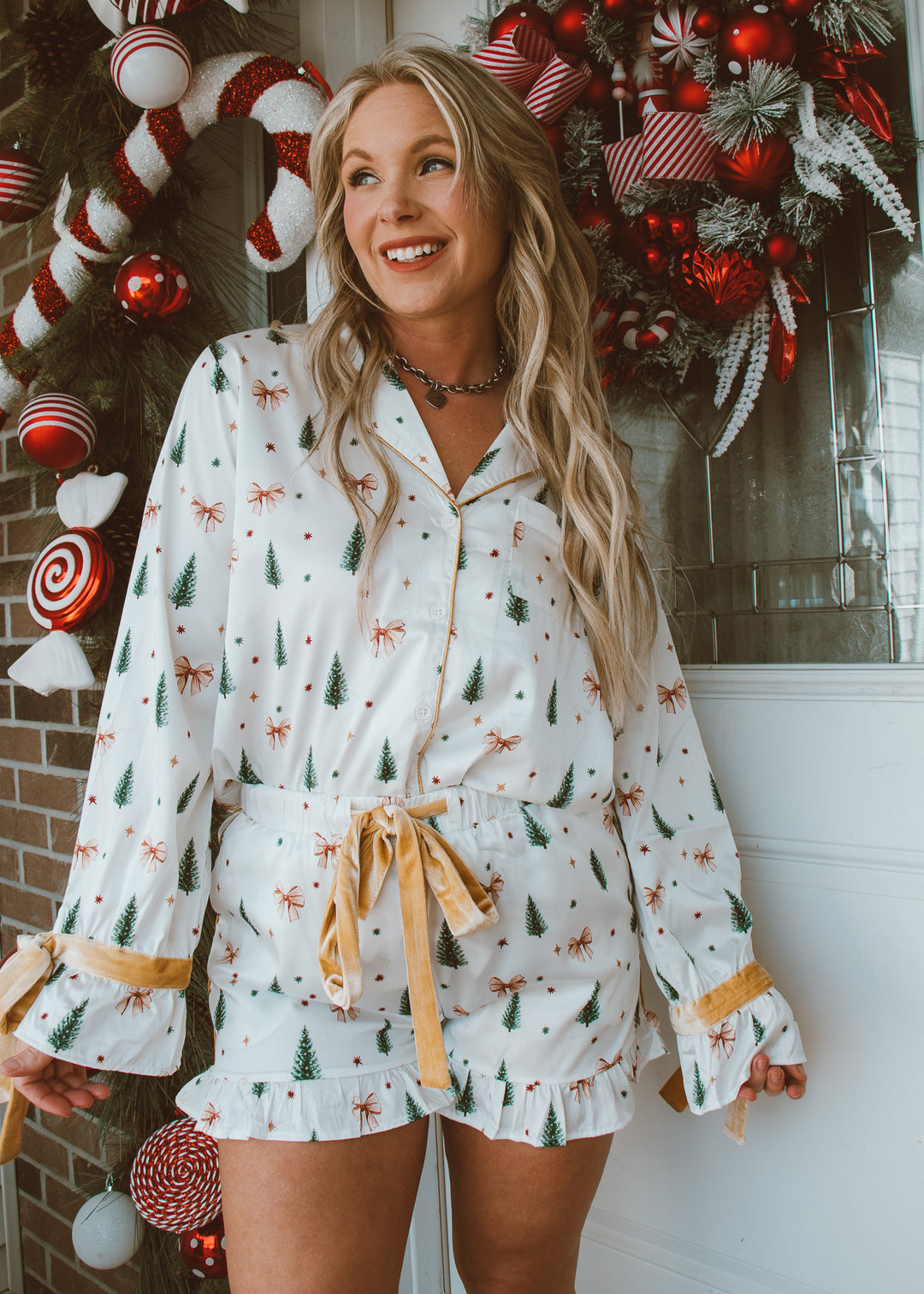 Woman wearing a festive pajama set with holiday decorations in the background