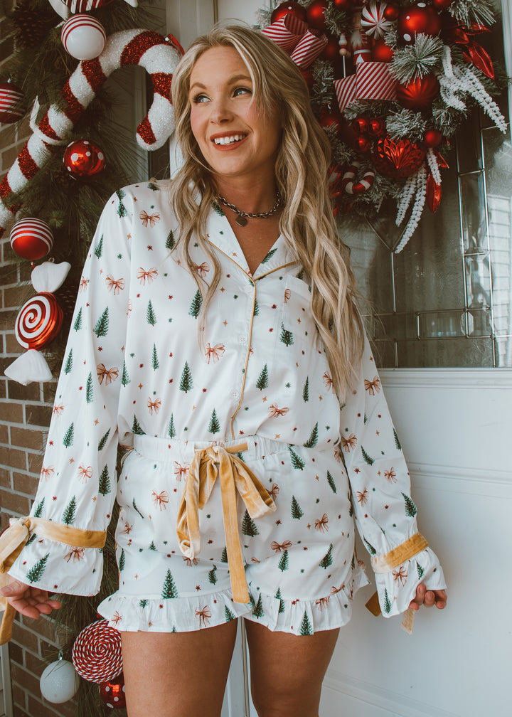 Woman wearing a festive pajama set with holiday decorations in the background