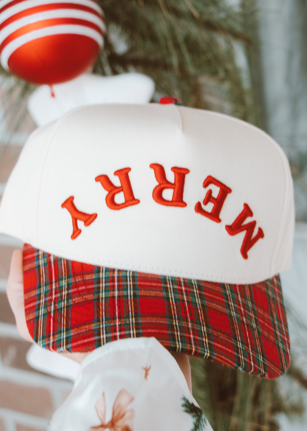 White stocking with red plaid trim and 'MERRY' text, Christmas tree in the background