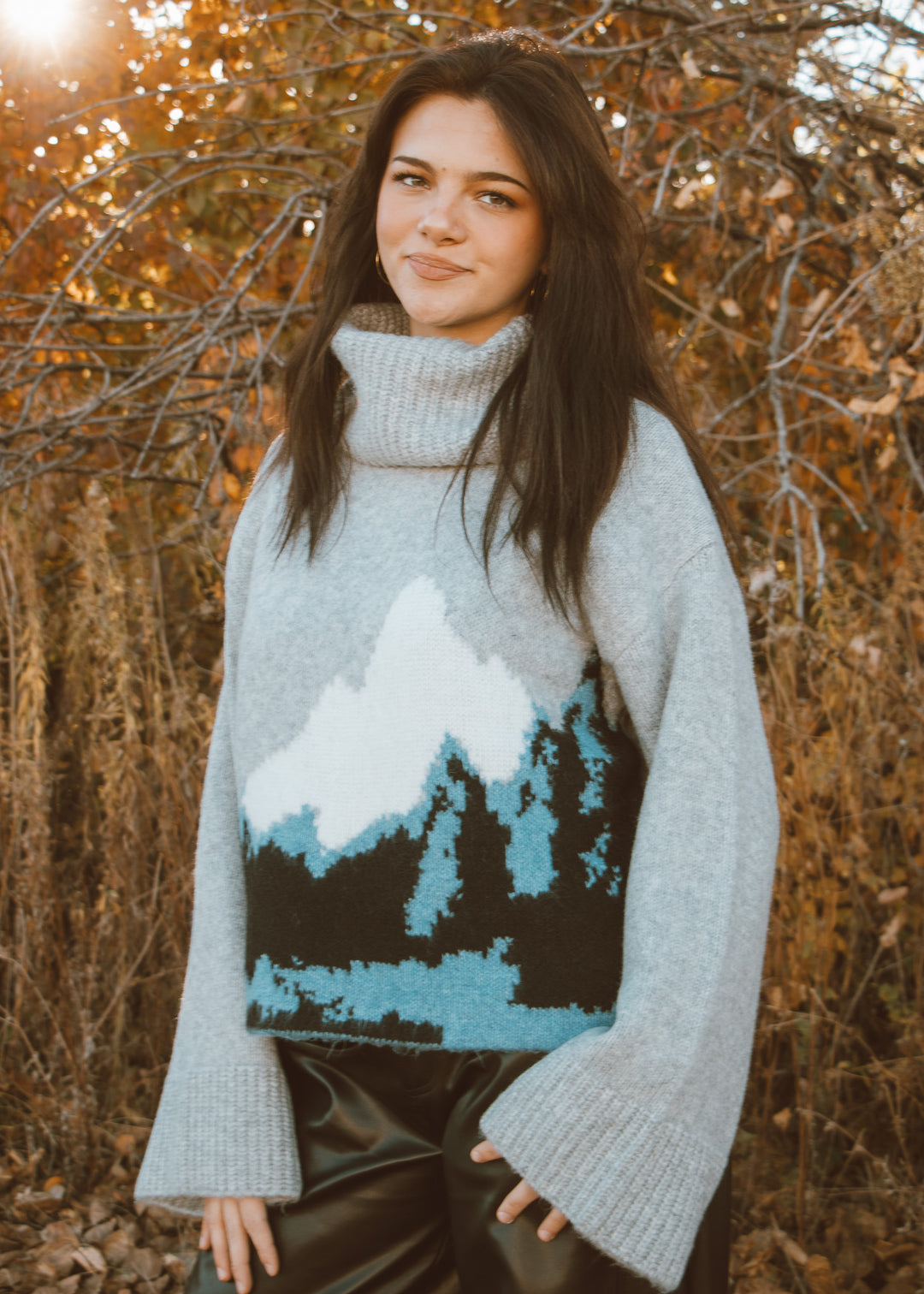 Woman wearing a sweater with a mountain design in an autumn setting