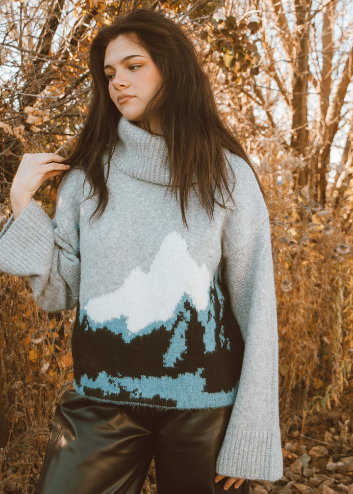 Woman wearing a sweater with a mountain design in an autumn setting