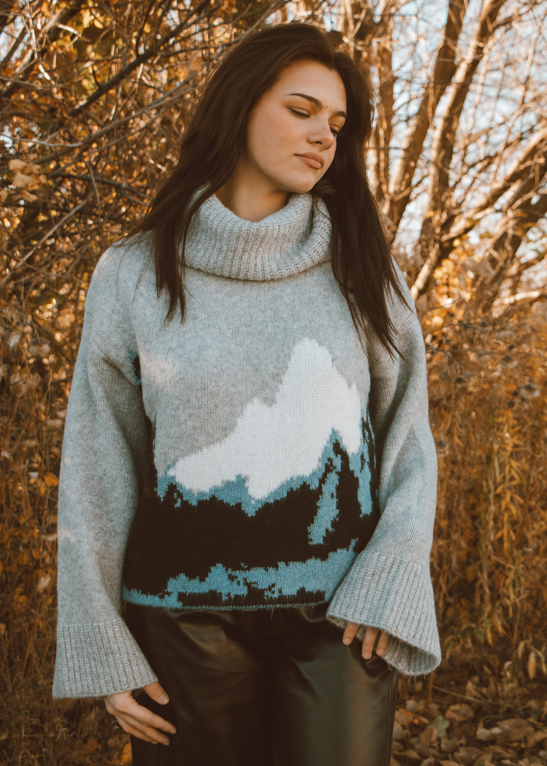 Woman wearing a sweater with a mountain design in an autumn setting
