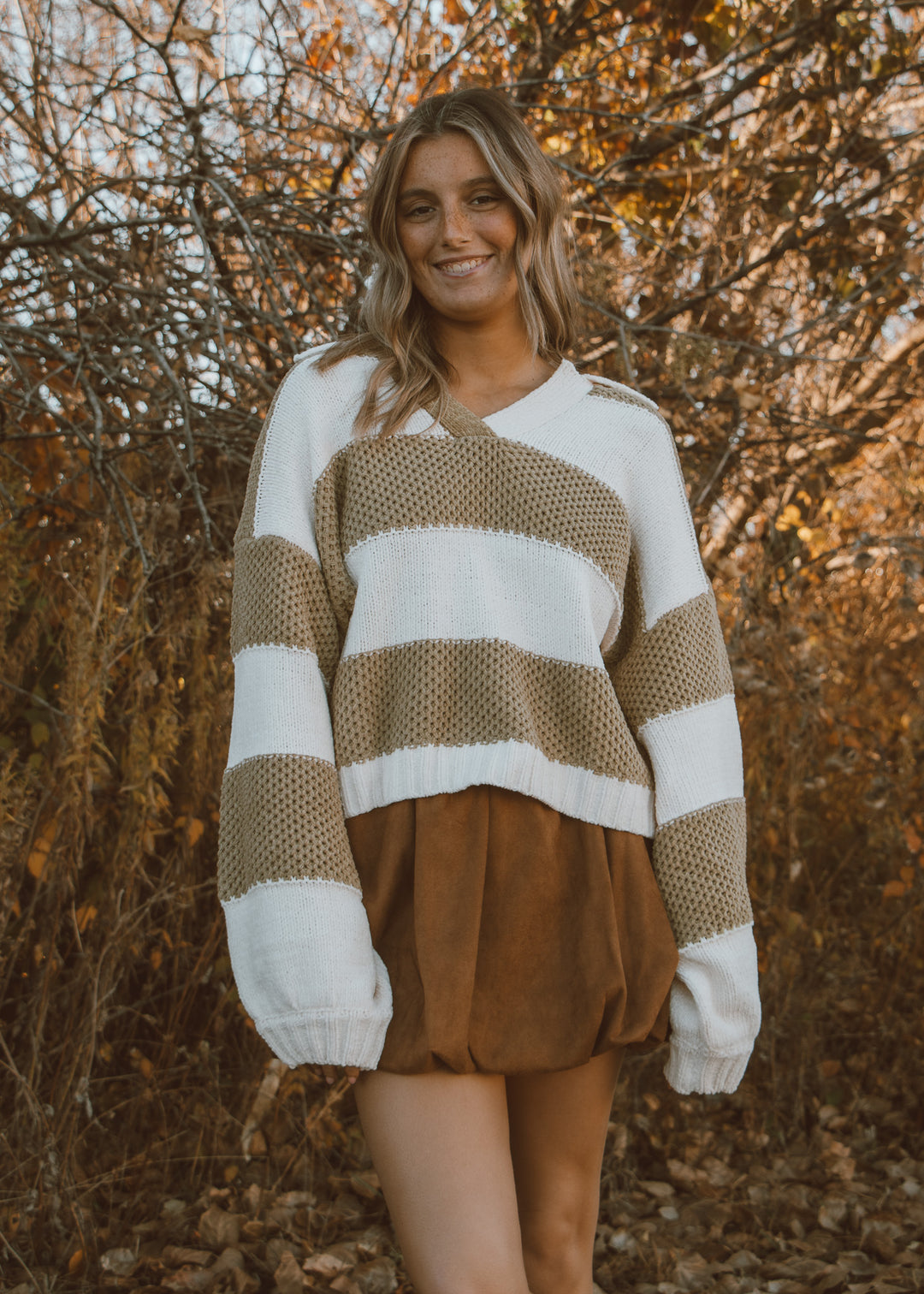 Woman wearing a green and white sweater with a brown bubble skirt.