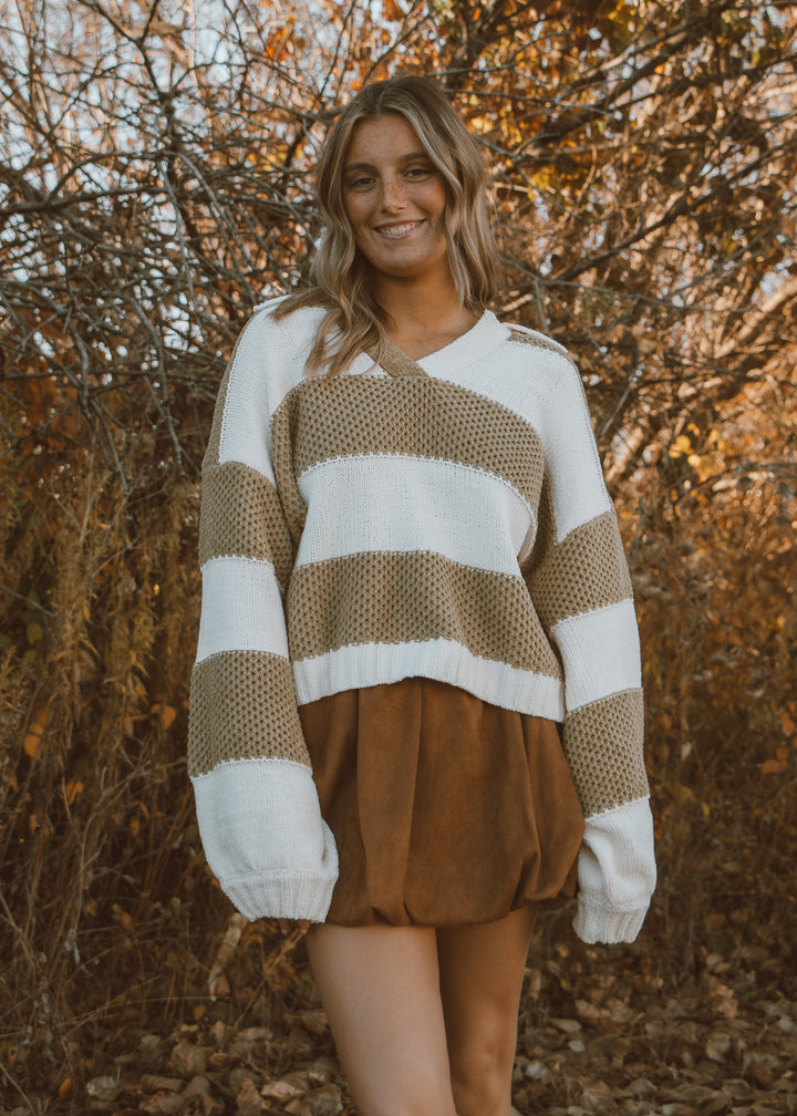 Woman wearing a green and white sweater with a brown bubble skirt.
