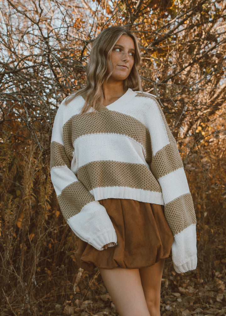 A green and white knit sweater and brown bubble skirt.