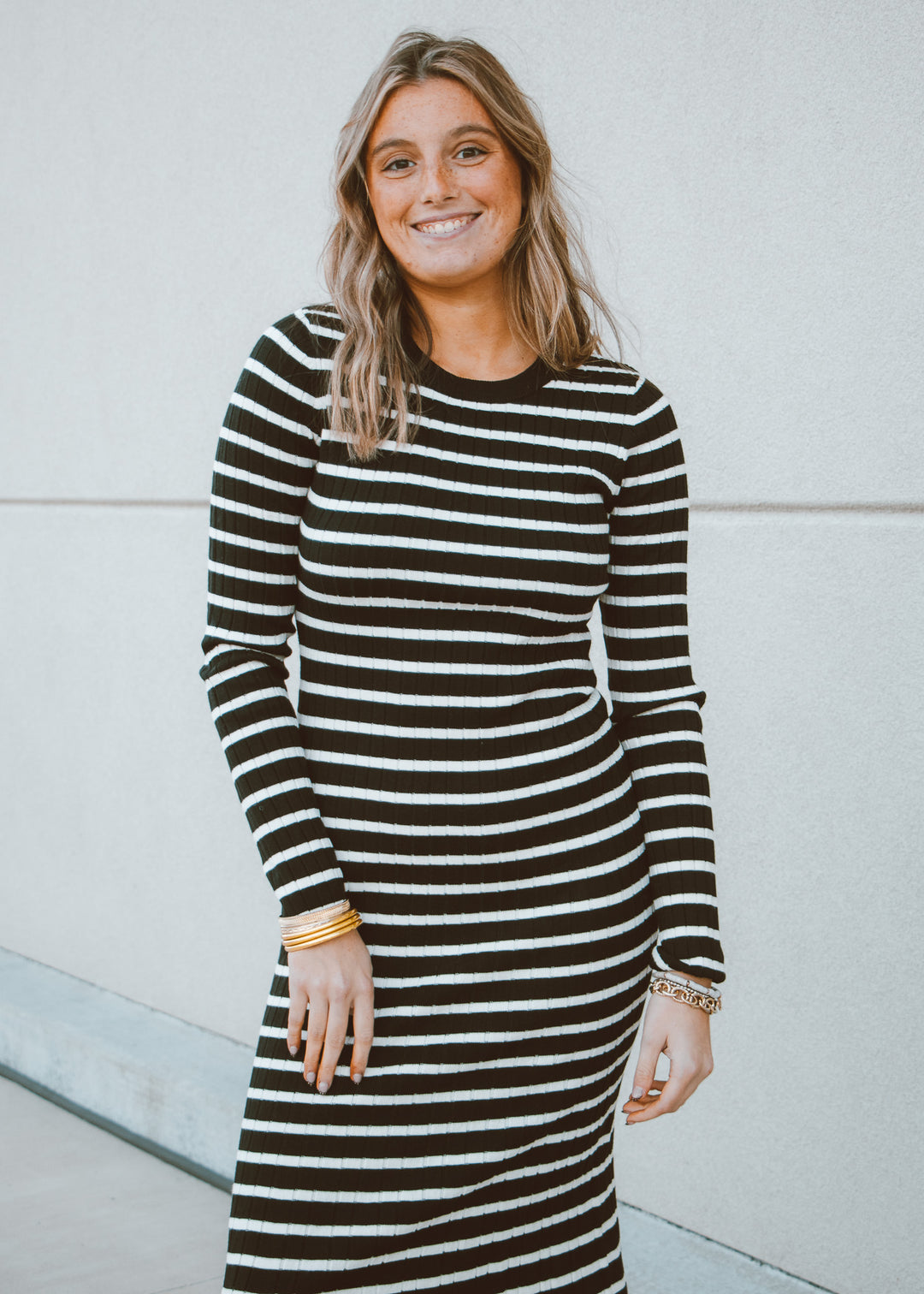 Woman wearing a black and white striped dress against a light background