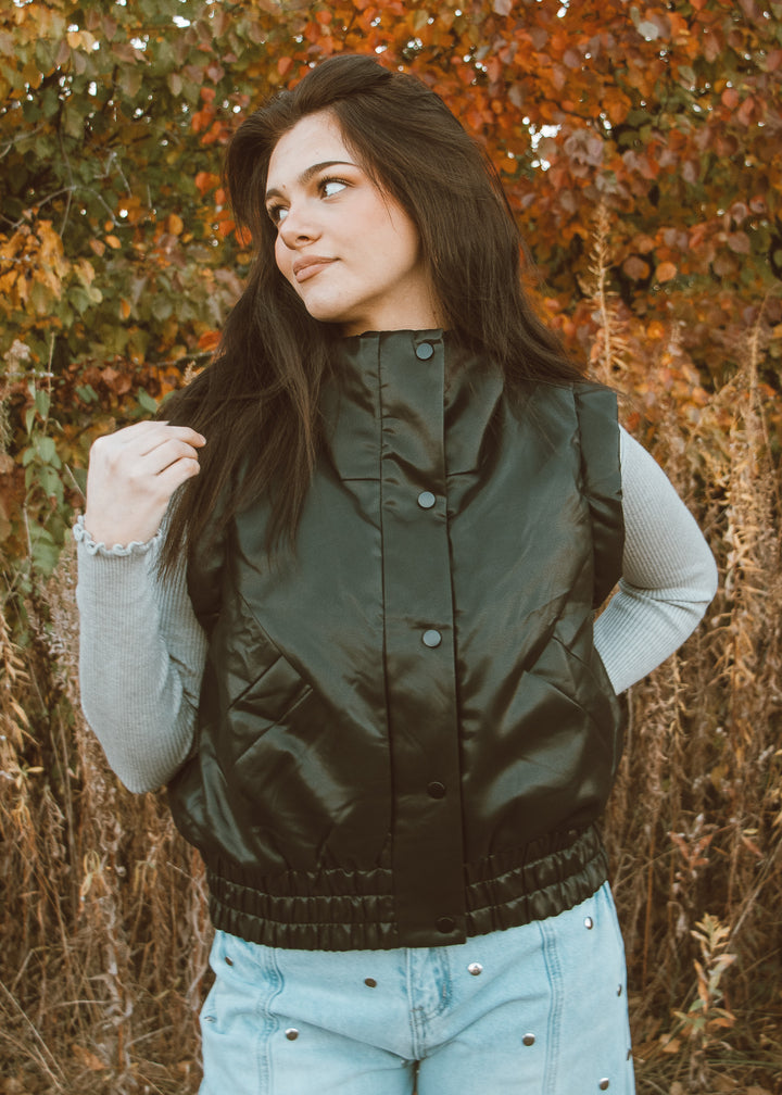 Woman wearing a green puffer vest in an autumn setting