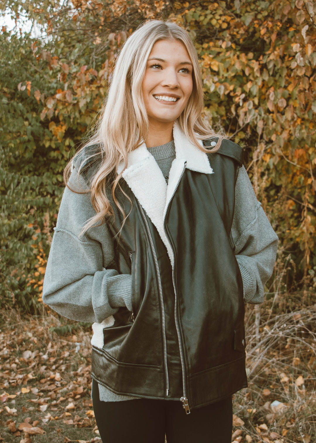 Woman wearing a green jacket with a white fur-lined hood in an autumn setting