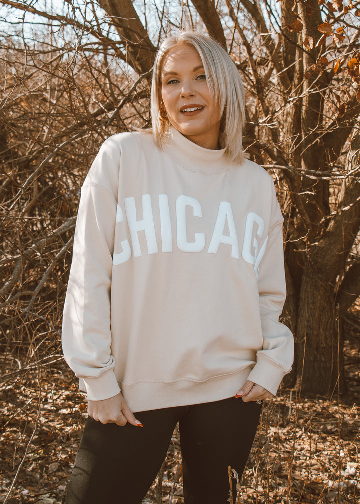 Person wearing a 'Chicago' sweatshirt standing in a wooded area.