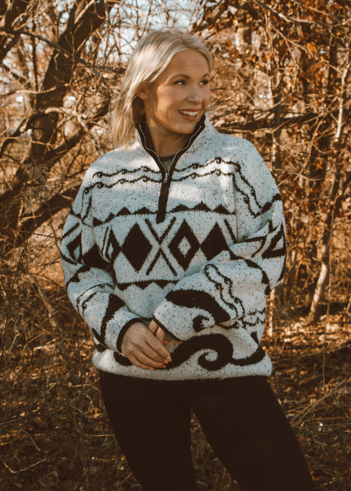 Woman wearing a patterned sweater standing in a forest