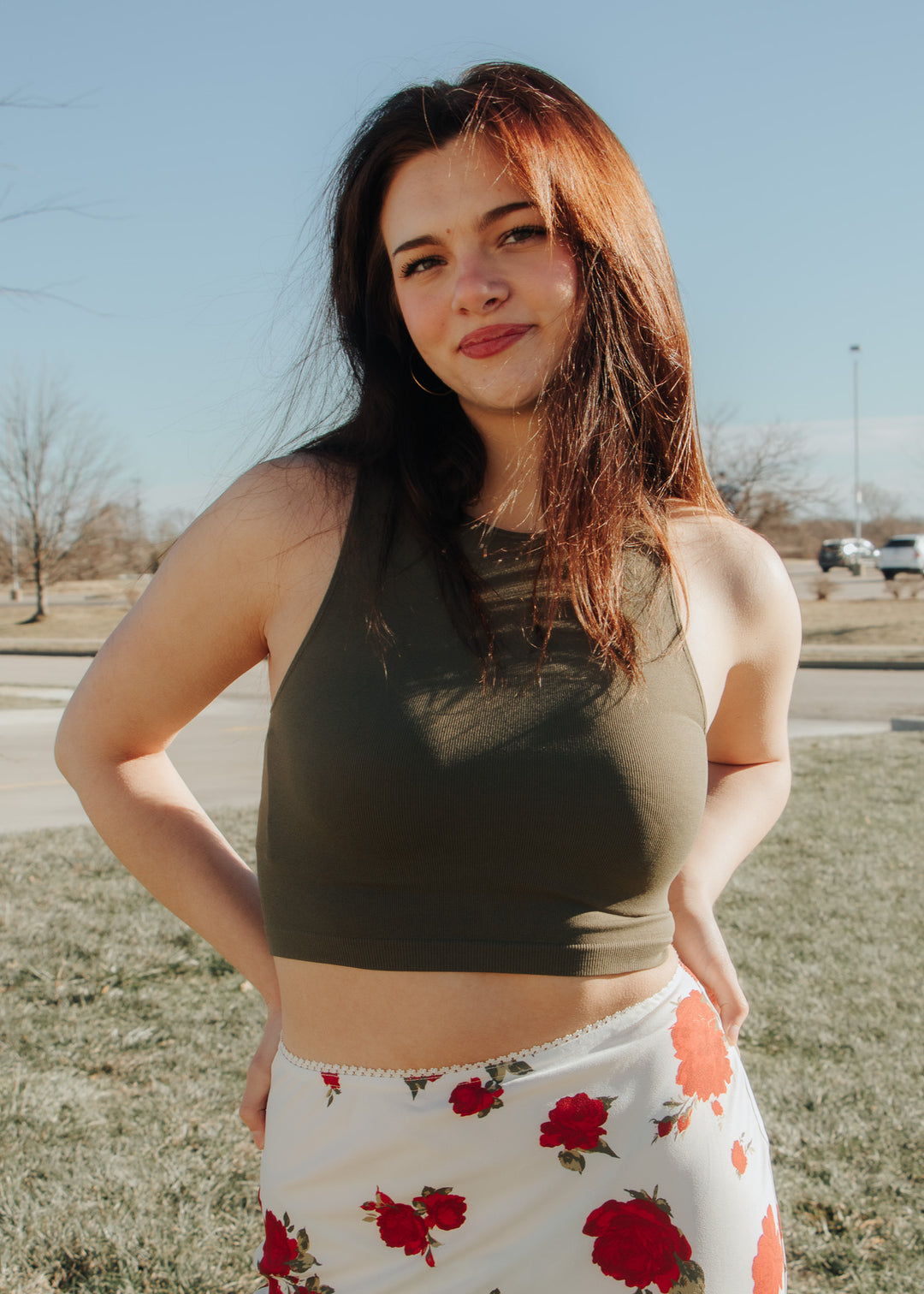 Woman wearing a green sleeveless top and floral skirt outdoors