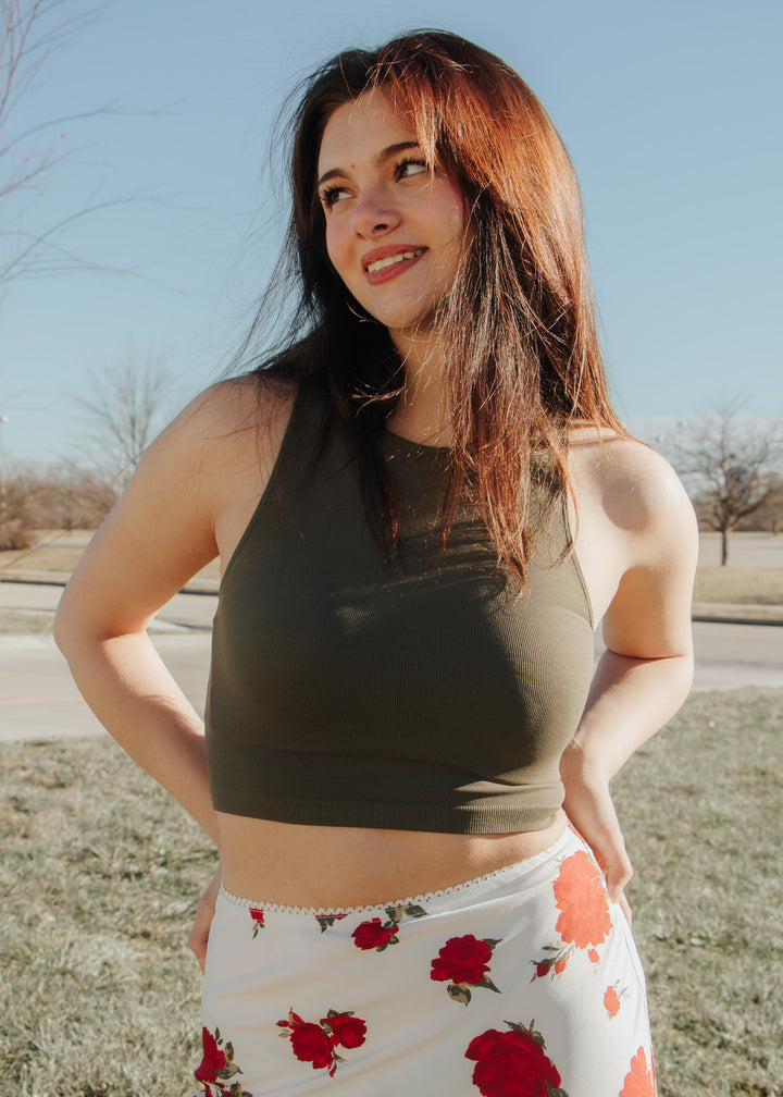 Woman wearing a green tank top and floral skirt outdoors