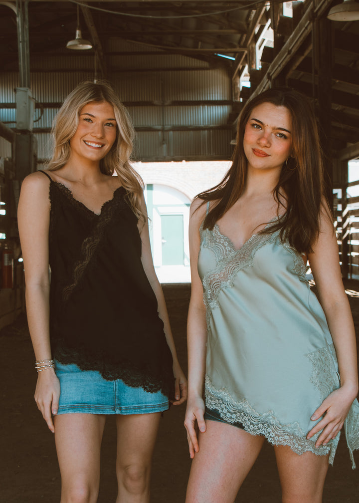 Two women standing side by side in a warehouse setting, wearing casual outfits.