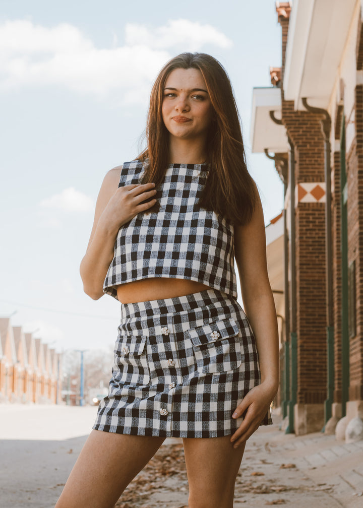 Woman wearing a navy and white checkered outfit standing outdoors.
