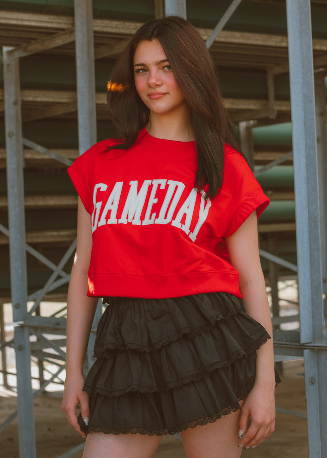 Woman wearing a red top with white embroidered lettering.