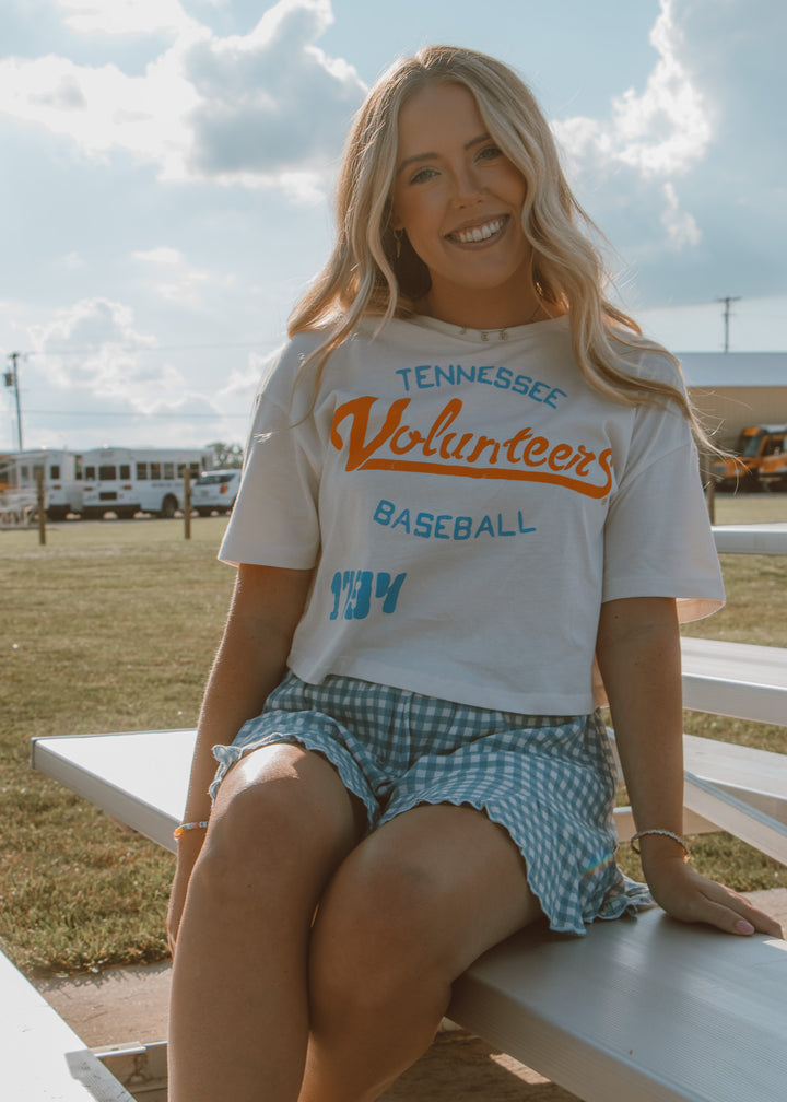 Woman wearing a 'Tennessee Volunteers Baseball' shirt sitting outdoors on a sunny day.