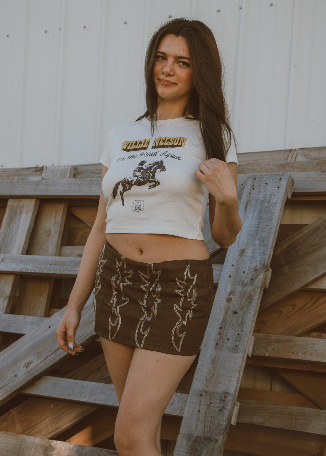 Woman wearing a graphic t-shirt and shorts standing on wooden steps.