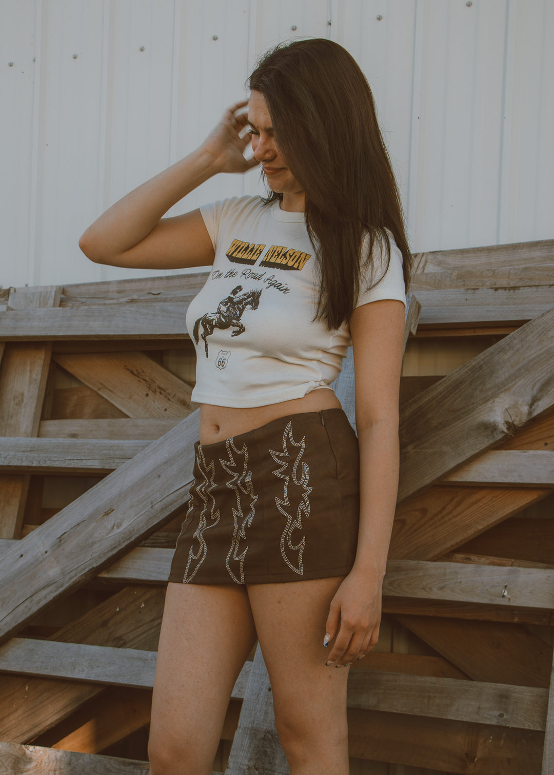 Woman wearing a graphic t-shirt and brown shorts standing on wooden steps.