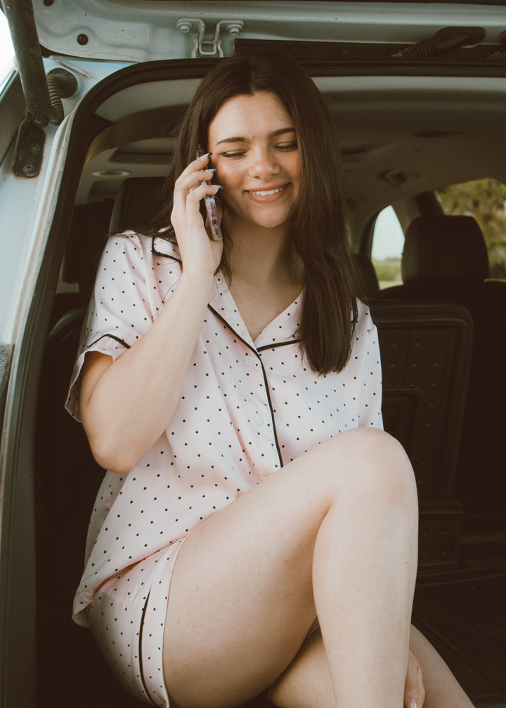 Woman in pajamas sitting in a car, talking on a phone