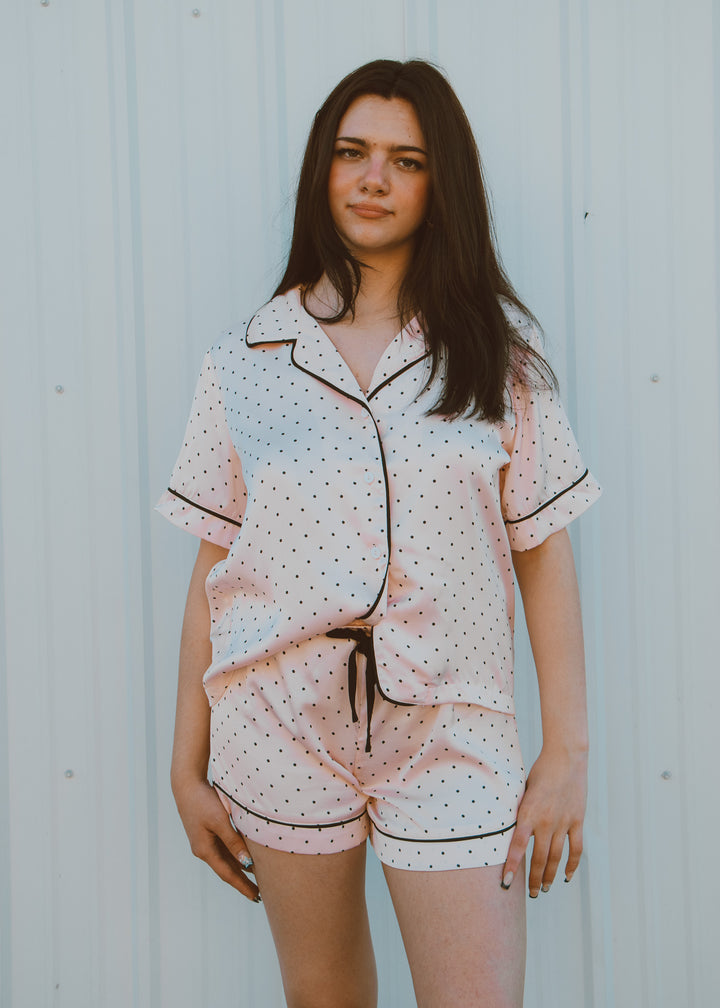 Woman wearing a polka dot pajama set against a light background