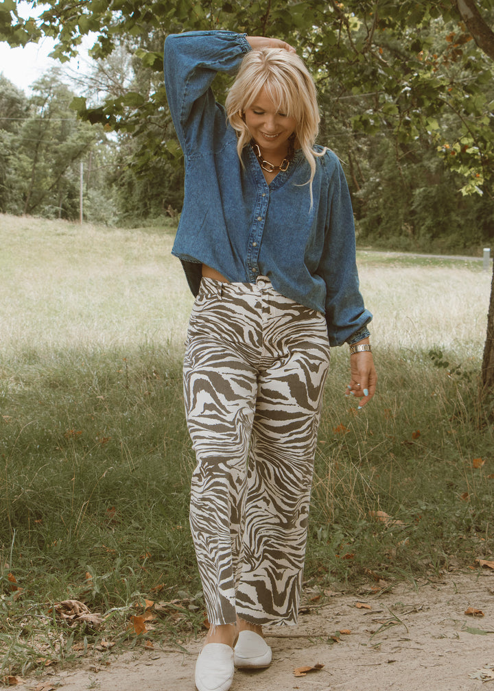 Woman in a blue shirt and zebra print pants walking outdoors.