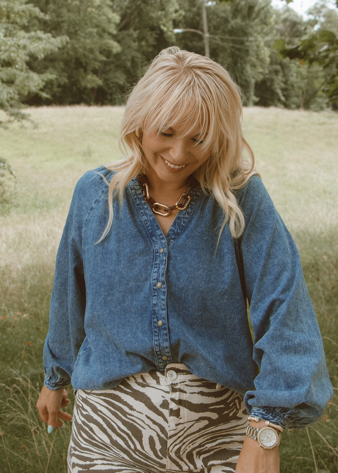 Woman wearing a blue denim shirt and zebra print skirt in a natural setting