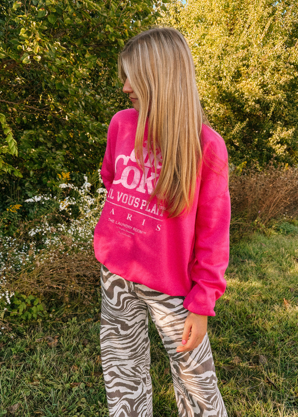 Person wearing a bright pink sweatshirt with text outdoors
