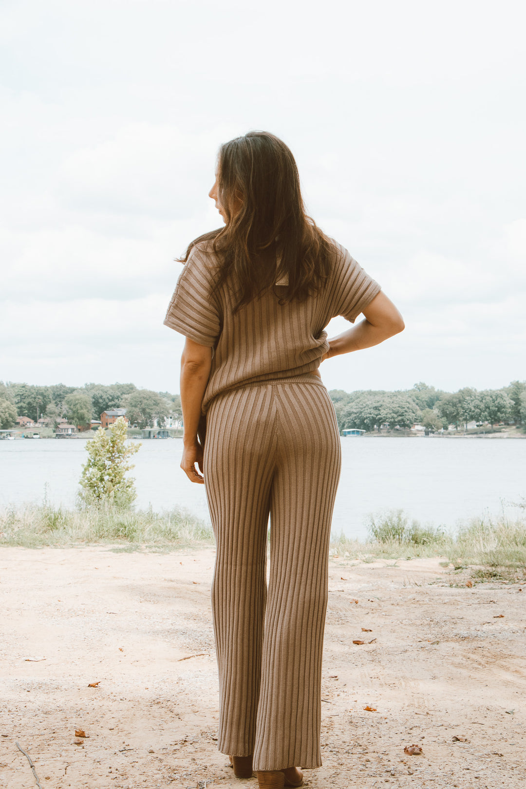Woman in a beige ribbed outfit standing by a lake