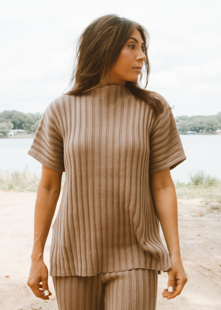 Woman wearing a ribbed brown top and pants outdoors.