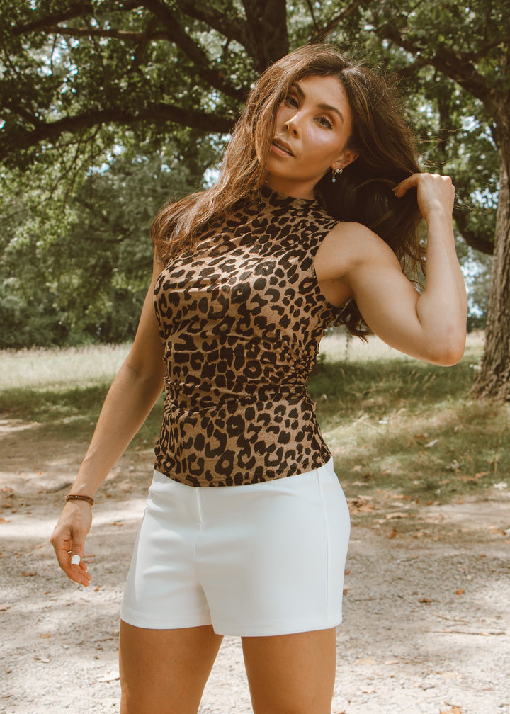 Woman wearing a leopard print top and white shorts outdoors