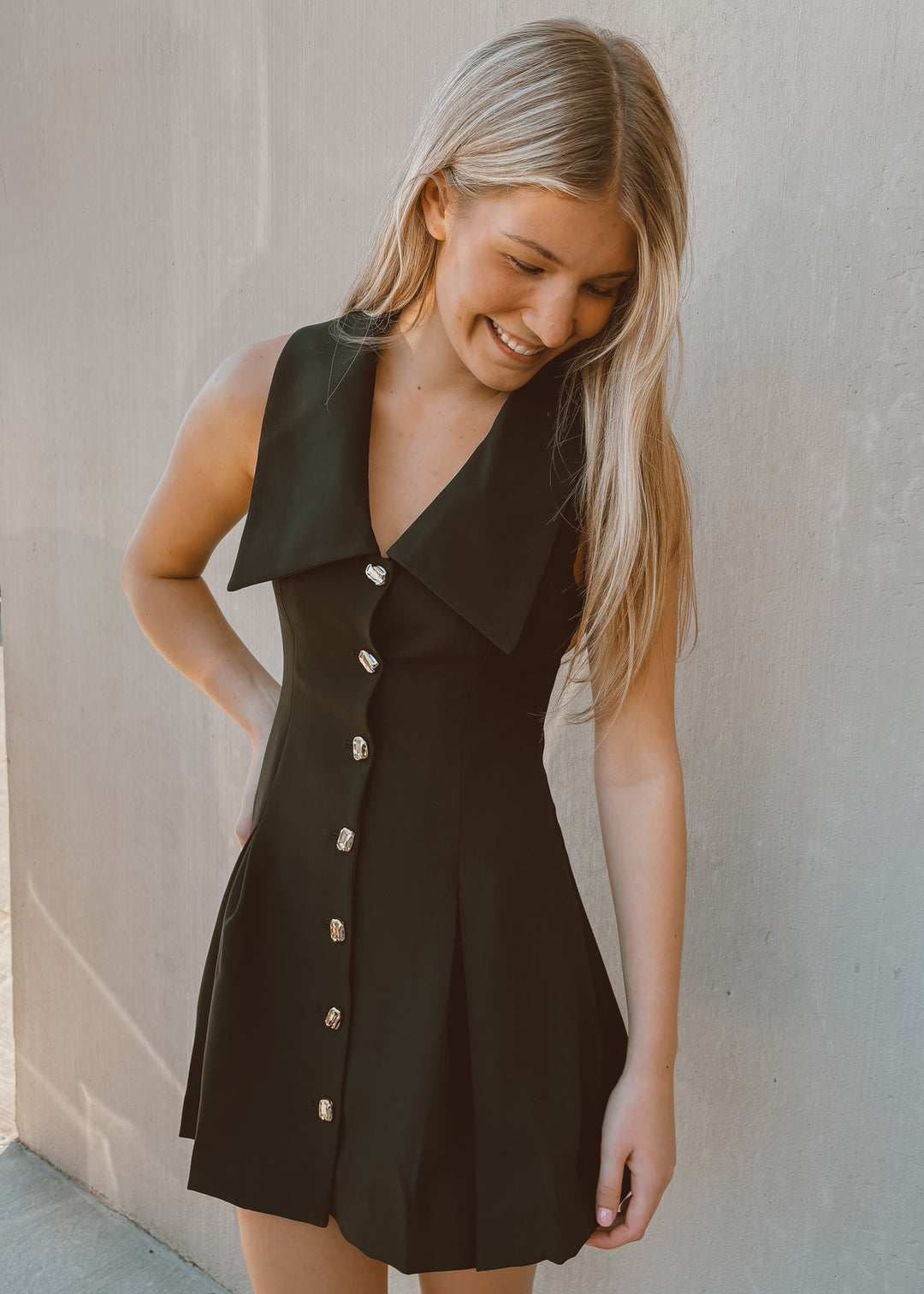 Woman wearing a black dress with buttons against a plain background
