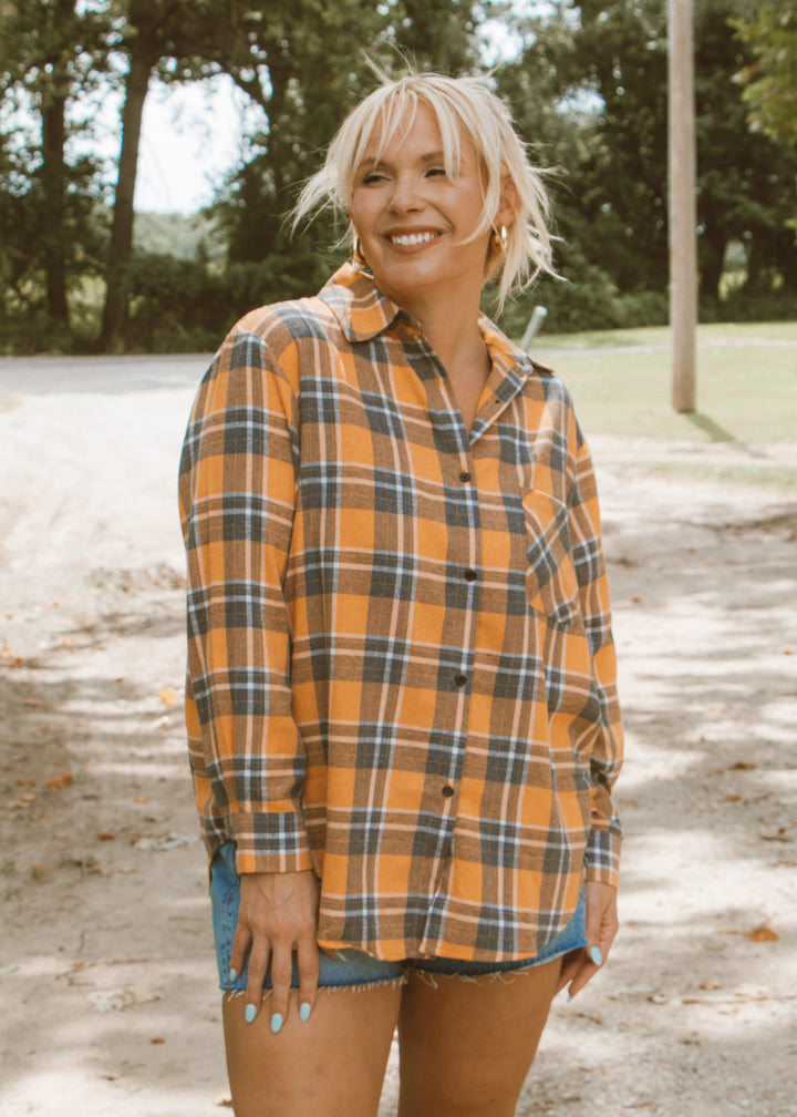 Person wearing a plaid shirt outdoors with trees in the background