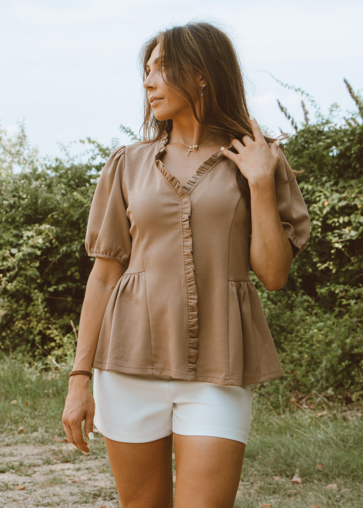 Woman wearing a brown blouse and white shorts outdoors